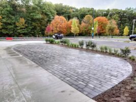 Curved paver walkway installation surrounded by fresh landscaping and colorful autumn trees, showcasing McLeod Landscaping's commercial hardscaping services.