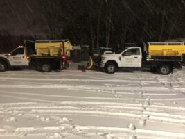 Commercial snow removal trucks from McLeod Landscaping clearing snow in a winter setting.
