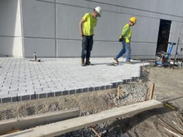 Workers installing pavers on a commercial landscaping project, showcasing hardscaping services by McLeod Landscaping.