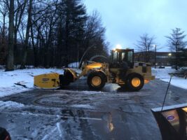 Commercial snow removal equipment clearing snow from a driveway, showcasing McLeod Landscaping's snow management services.