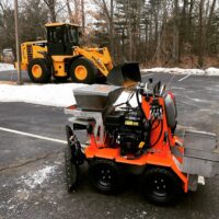Commercial snow removal equipment, including a snow plow and a loader, parked on a snowy lot, showcasing McLeod Landscaping's snow management services.