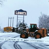 Commercial snow removal equipment clearing snow in front of Lowe's store, showcasing McLeod Landscaping's snow management services.