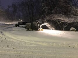 Commercial snow removal equipment clearing snow in a winter landscape at night, showcasing McLeod Landscaping's snow management services.
