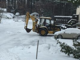 Commercial snow removal equipment clearing snow from a residential driveway, showcasing McLeod Landscaping's snow management services.