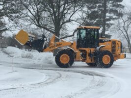 Commercial snow removal equipment clearing snow from a residential area, showcasing McLeod Landscaping's snow management services.