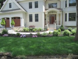 Residential landscaping project featuring a well-maintained lawn, colorful flower beds, and a welcoming entrance to a home, showcasing McLeod Landscaping's design expertise.