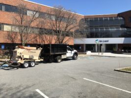 Commercial landscaping truck and equipment parked outside a modern office building, showcasing McLeod Landscaping's services and maintenance operations.