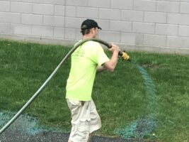 Man watering grass with hose in commercial landscaping project by McLeod Landscaping.