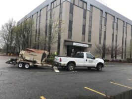 White pickup truck with trailer parked outside a commercial building, showcasing McLeod Landscaping's commercial landscaping and maintenance services.