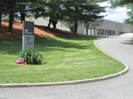 Commercial landscaping installation featuring manicured lawn, signage, and surrounding trees at McLeod Landscaping property.