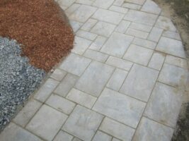 Paved walkway featuring stone tiles, bordered by decorative gravel and mulch, showcasing McLeod Landscaping's hardscape design expertise.