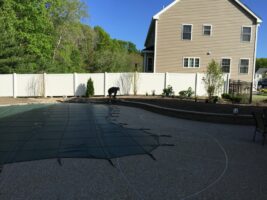 Residential landscaping project featuring a covered pool area, stone patio, and a worker preparing the site, showcasing McLeod Landscaping's design and construction services.