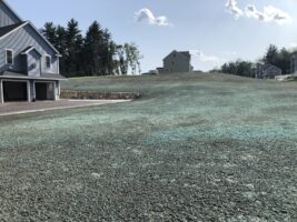 Residential landscaping project featuring freshly laid sod and a newly graded lawn, with a house and neighboring structures in the background, showcasing McLeod Landscaping's services.