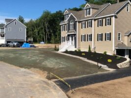 Residential landscaping project featuring a newly constructed home with freshly laid sod and decorative stonework, showcasing McLeod Landscaping's design and installation services.