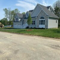 Residential landscaping project showcasing a newly constructed home with manicured lawn and trees, highlighting McLeod Landscaping's design and installation services.