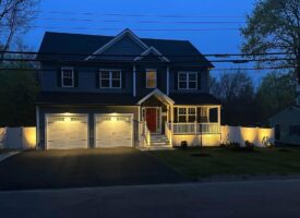 Residential landscaping project featuring a well-lit home facade with a welcoming entrance, illuminated driveway, and manicured front yard, showcasing McLeod Landscaping's design and installation services.